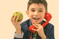 Studio shot of cute happy boy smiling and holding green apple while talking on old telephone Royalty Free Stock Photo