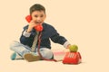 Studio shot of cute happy boy smiling while talking on old telephone and holding gift box Royalty Free Stock Photo