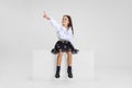 Studio shot of cute little girl in casual clothes sitting on big box isolated on white background. Royalty Free Stock Photo