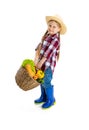 Studio shot of cute little girl, emotive kid in image of farmer, gardener holding big basket of vegetables isolated on