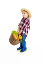 Studio shot of cute little girl, emotive kid in image of farmer, gardener holding big basket of vegetables isolated on