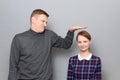 Tall man is showing height of short woman, people of different heights Royalty Free Stock Photo