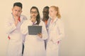 Studio shot of diverse group of multi ethnic doctors thinking while reading on clipboard together Royalty Free Stock Photo