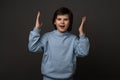 Studio shot of emotional surprised young boy standing with open mouth, raising palms high and shouting from happiness Royalty Free Stock Photo