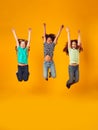 Studio Shot Of Energetic Children Jumping In The Air With Outstretched Arms On Yellow Background Royalty Free Stock Photo