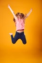 Studio Shot Of Energetic Girl In The Air With Outstretched Arms Against Yellow Background Royalty Free Stock Photo