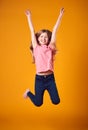 Studio Shot Of Energetic Girl In The Air With Outstretched Arms Against Yellow Background Royalty Free Stock Photo