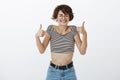 Studio shot of excited happy and pleased cute female with short brown hair, closing eyes and smiling joyfully while