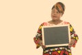 Studio shot of fat black African woman thinking while holding blank blackboard Royalty Free Stock Photo