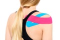 Studio shot of a female patient with kinesio tape on her shoulder and back, isolated over white. Kinesiology, physical therapy.