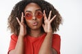 Studio shot of flirty and feminine attractive african-american woman in red t-shirt and stylish round sunglasses folding Royalty Free Stock Photo