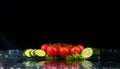 Studio shot with freeze motion of cherry tomatoes and slices of cucumber in water splash on black background Royalty Free Stock Photo