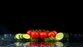 Studio shot with freeze motion of cherry tomatoes and slices of cucumber in water splash on black background Royalty Free Stock Photo