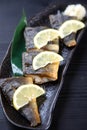 Studio shot of grilled atka mackerel with lemon on dark background