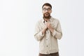 Studio shot of handsome friendly and emotive adult male with long beard and moustache being touched and grateful holding