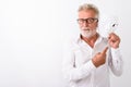 Studio shot of handsome senior bearded man holding white mask ne Royalty Free Stock Photo