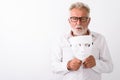 Studio shot of handsome senior bearded man holding white mask wh Royalty Free Stock Photo