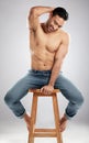 Strong abs for a soft heart. Studio shot of a handsome young man showing off his muscular body while sitting on a chair Royalty Free Stock Photo