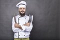 Studio shot of a happy bearded young chef holding sharp knives Royalty Free Stock Photo