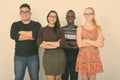 Studio shot of happy diverse group of multi ethnic friends smiling with arms crossed while wearing eyeglasses together