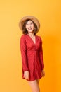 Studio shot of happy energetic asian woman wearing red dress and straw hat over orange background Royalty Free Stock Photo