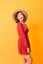 Studio shot of happy energetic asian woman wearing red dress and straw hat over orange background Royalty Free Stock Photo