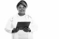 Studio shot of happy fat black African woman doctor smiling and holding clipboard while thinking Royalty Free Stock Photo