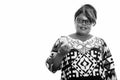 Studio shot of happy fat black African woman smiling while holding mobile phone and thinking Royalty Free Stock Photo