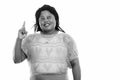 Studio shot of happy fat black African woman smiling and thinking while pointing finger up Royalty Free Stock Photo