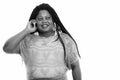 Studio shot of happy fat black African woman smiling and thinking while talking on mobile phone Royalty Free Stock Photo