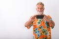 Studio shot of happy senior bearded tourist man smiling while ta Royalty Free Stock Photo