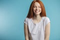 Female model with red loose hair and natural make-up posing over blue background. Royalty Free Stock Photo