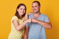 Studio shot of happy smiling young woman and man couple give fist bump looking at camera with peasant facial expression, being Royalty Free Stock Photo