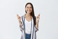 Studio shot of joyful happy and carefree woman in glasses and striped blouse, smiling joyfully with closed eyes, being