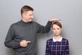 Tall man is showing height of short woman and pointing at her Royalty Free Stock Photo