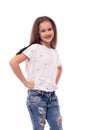 Studio shot of a little girl wearing jeans and white blouse on white background. She stands and holds her hands on hips