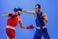 Studio shot of male professional boxers in red and blue sports uniform boxing isolated on blue background in neon light Royalty Free Stock Photo