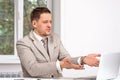 Studio shot of a man wearing a beige jacket and a tie working on a laptop with something dissatisfied or indignant, pointing with Royalty Free Stock Photo