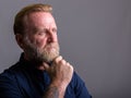 Studio shot of mature bearded man with hand tattoos thinking