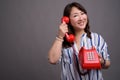 Mature beautiful Asian businesswoman holding old red phone Royalty Free Stock Photo
