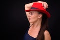 Mature beautiful woman wearing red fedora hat against black background Royalty Free Stock Photo