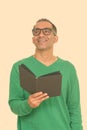 Mature happy Persian man holding book while thinking Royalty Free Stock Photo