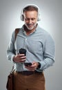 Hes a go-getter whos always prepared for the day. Studio shot of a mature man wearing headphones and using a cellphone Royalty Free Stock Photo