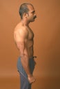 Muscular Indian man with mustache shirtless against brown background