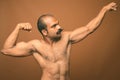 Muscular Indian man with mustache shirtless against brown background