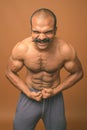 Muscular Indian man with mustache shirtless against brown background