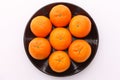 Top view of 7 orange fruit citrus tankan on black dish on white background