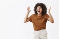 Studio shot of over-emotive carefree and happy stylish modern african american female in trendy brown t-shrit gesturing Royalty Free Stock Photo