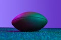 Studio shot of professional ball for american football game isolated over purple background in neon lights