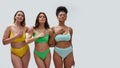 Studio shot of proud young women in colorful underwear with different body shapes showing four fingers gesture, Fourth